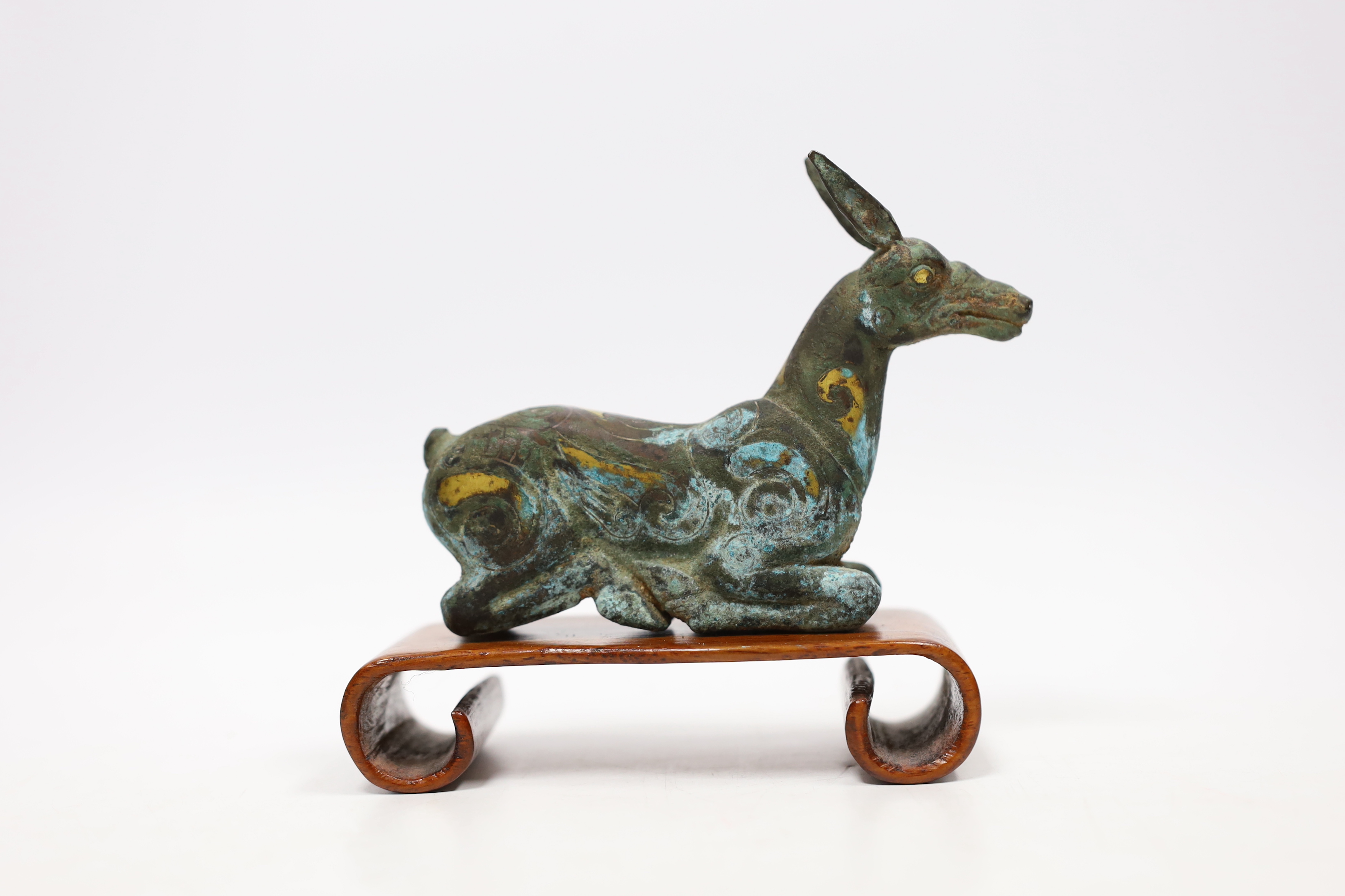 A Chinese bronze and parcel gilt Han style figure of a seated deer, and a small Etruscan terracotta head on stand
